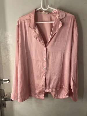 Ljusrosa skjorta med knappar - Ljusrosa skjorta i silkes mjukt material med klassisk krage och knäppning framtill. Skjortan har lång ärm och en avslappnad passform som ger en chill vibe. Perfekt att styla med jeans eller kjol för en enkel look. Funkar både som fest skjorta men även som pyjamas skjorta:)👚 