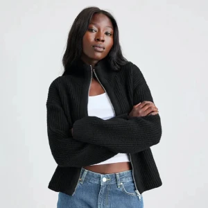 Svart stickad kofta med dragkedja från bikbok - Svart ribbstickad kofta med hög krage och hel dragkedja framtill. Från bikbok jättebra skick endast testad