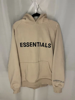  Essentials Fear of God (hoodie & byxor) - Säljer ett par beige mjukisbyxor från Essentials Fear of God i storlek M. Byxorna har elastisk midja med snörning, muddar vid benslut och sidofickor. Materialet är mjukt och skönt, perfekt för chill dagar. Logga tryckt på benet.