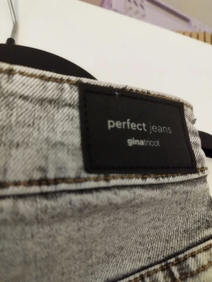 Grå wide jeans från Gina Tricot - Säljer ett par ljusgrå jeans från Gina Tricot, modell 'Perfect Jeans'. Byxorna har hög midja och breda ben för en chill och trendig look. Klassisk femficksdesign och knapp- samt dragkedja framtill. Materialet är jeans med snygg tvättad finish.