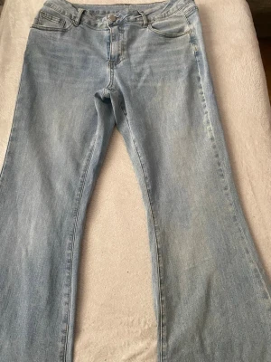 Ljusblå bootcut jeans - Säljer ett par ljusblå jeans med klassisk skolstil med Y2k stil och bootcut-ben. Jeansen har normal passform och är tillverkade i mjukt denimtyg. Perfekta för dig som gillar retrovibbar och vill ha ett par riktigt snygga jeans med utsvängda ben.