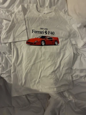 Vit Ferrari F40 t-shirt - Säljer en vit t-shirt med tryck av en röd Ferrari F40 och texten '1987-1992 Ferrari F40' på bröstet. Helt ny finns i storlek S och M, riktigt grisch