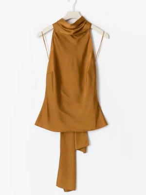 Mustardgul halterneck blus med rosett - Säljer en helt ny halterneck blus från Gina Tricot i en djup orange/gul färg. Blusen har en lång scarf-detalj som kan knytas till rosett i nacken och även framtill. Modellen har samt öppen rygg.