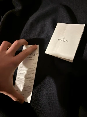 Svart bomberjacka från Moncler - Säljer en svart bomberjacka från Moncler med klassisk logga på ärmen och snygga detaljer i blankt material vid kragen. Jackan har dragkedja, fickor med tryckknappar och en clean, modern look. Perfekt för dig som vill ha något stilrent och exklusivt. kvitto finns även köpt i italien 