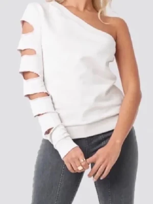 Vit oneshoulder topp med cutouts - Säljer en vit/beige oneshoulder topp med lång ärm och coola håldetaljer längs hela ärmen. Storlek M men passar snarare S från AFJ x NA-KD. Materialet är bomull.
