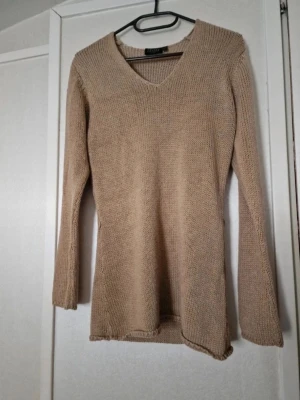 Beige/brun stickad v-ringad tröja - Beige stickad tröja från Lindex med v-ringning och lång ärm. Tröjan har en loose passform och är perfekt för lager-på-lager. Mjuk och skön känsla, passar till jeans eller kjol. Maskorna är lite skadade på några ställen (se bilder). Stl S