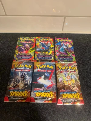 Pokémon 6st booster paket - Säljer 6st nya booster paket. 3x Surging Sparks & 3x Phantasmal Flames. Sealed. Skickas väl skyddat 