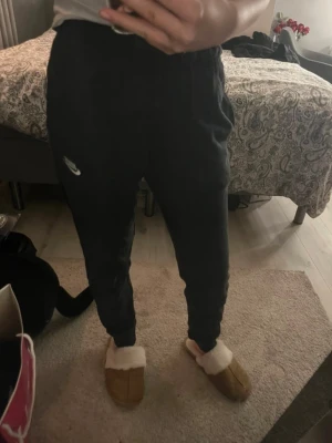 Svarta Nike mjukisbyxor – klassisk modell - Svarta mjukisbyxor från Nike i bekväm och avslappnad modell. Resår och dragsko i midjan för bra passform samt Nike-logga på benet. Perfekta som vardagsbyxor, till träning eller som mysbyxor. Använda men i bra skick.