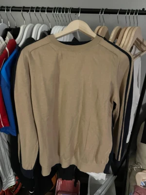 Beige och marinblå tröja Lawrence Grey - Snygg beige tröja från Lawrence Grey med marinblå detaljer längs ärmarna och halsen. Tröjan har rund hals och är långärmad, perfekt för dig som gillar stilrena och enkla plagg. Materialet känns mjukt och är troligen bomull eller en bomullsblandning.