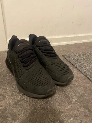 Nike Air Max 270 svarta sneakers - Nike Air Max 270 sneakers i helsvart färg med mesh-överdel och synlig Air-enhet i hälen. Snygg sportig design med snörning och rund tå. Perfekt för dig som gillar streetstyle och vill ha bekväma skor med grym dämpning. 7/10 skick skickas samma dag och är gör rent dem innan jag skickar