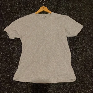 Grå t-shirt från Sunspel i bomull - Snygg grå t-shirt från Sunspel, tillverkad i Portugal. Modellen är klassisk med rund hals och korta ärmar, perfekt för en clean och enkel stil. Materialet är mjuk bomull som känns skönt mot huden. Passar dig som gillar minimalistiska plagg med premiumkänsla.