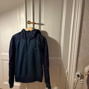 Mörkblå hoodie från J.Lindeberg - Snygg mörkblå hoodie från J.Lindeberg med huva och snörning. Passar perfekt under en väst eller liknande nu på hösten då den är i ett lite varmare material. Skriv för frågor eller fler bilder. Öppen för prisförslag 