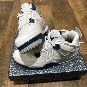 Nike Air Jordan 4 Retro Midnight Navy - Nike Air Jordan 4 Retro i färgen White/Midnight Navy. Snygga sneakers med vit ovandel i skinn, marinblå och grå detaljer, meshpaneler och klassisk Jumpman-logga på plösen och hälen. Platt sula med röd detalj undertill och snörning framtill. Perfekt för dig som gillar streetwear. Är du osäker på priset, så kan det diskuteras👍