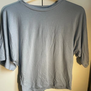 Ljusblå  t-shirt, tight vid botten och lös vid toppen - En ljusblå T-shirt som är tight vid botten av tröjan och lös vid toppen. De är i storlek s men skulle säga att den passar både m och xs eftersom den är extremt stretchig. Inte alls använd mycket, kanske 2-3 gånger🥰 Skriv ifall ni vill se fler bilder av tröjan eller om ni vill se den på!💕 