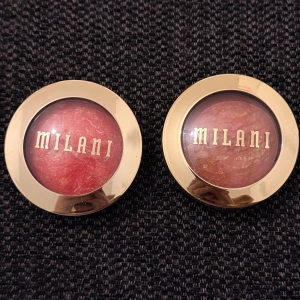 Milani Baked Blush Coralina & Berry Amore - Två Milani Baked Powder Blush i färgerna 08 Coralina (korallröd med guldskimmer) och 03 Berry Amore (bärig rosa med guldinslag). Båda har marmorerad finish och kommer i rund guldfärgad plastförpackning med transparent lock. Endast testade 