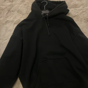 Svart hoodie från BikBok XS - Svart hoodie från BikBok i storlek XS. Tröjan har en klassisk huva med snörning och en stor magficka framtill. Mjuk insida och långärmad modell. 