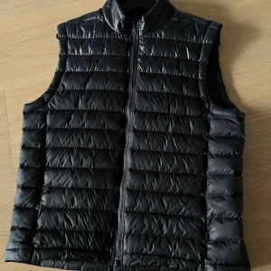 Svart dunväst från J.Lindeberg - Storlek L men passar M. Jag kör alltid med M. Är 180 cm lång väger ca 80 kg. 