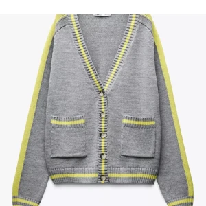 Grå kofta med gula ränder från Zara - Grå kofta med ljusgula ränder längs ärmar, muddar och knappslå. V-ringad med ribbade detaljer och stora knappar framtill. Två fickor fram med gul rand. Stickad i mjukt material, perfekt för lager-på-lager och chill stil.