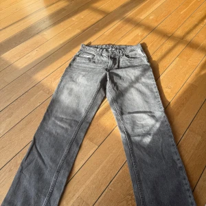 Grå raka jeans med klassisk look - Snygga grå jeans med rak passform och klassisk femficksdesign. Jeansen har en cool tvättad look och är tillverkade i jeansmaterial. Perfekta för dig som gillar en enkel och stilren vibe. Passar till sneakers eller boots.