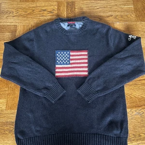 Mörkblå stickad tröja från GANT - Mörkblå stickad tröja från GANT med amerikansk flagga broderad på bröstet och vit GANT-logga på ena ärmen. Rund hals och ribbade muddar vid ärmslut och nederkant. Perfekt för dig som gillar klassisk college-stil. Nypris ligger på 1500kr mitt pris 550kr, pris går att diskutera vid snabb affär!!