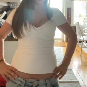 Vit v-ringad topp med kort ärm - Säljer en stilren vit topp med v-ringad hals och korta ärmar. Använd 1-2 gånger, storlek xs💕