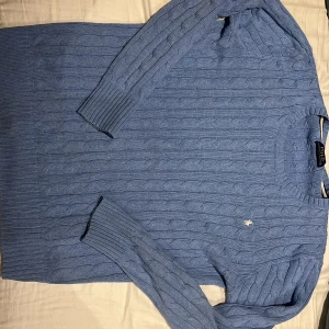Blå kabelstickad tröja Polo Ralph Lauren - Säljer nu kabelstickade Ralph lauren tröja som jag slutat använda, den är i ljusblå färg som gör den lite mer speciell men är ursnygg! Vid minsta lilla fundering hör gärna av dig.