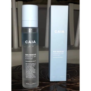 CAIA SOS Rescue Glowing Oil Mist - Fräsch oljemist från CAIA, SOS Rescue Glowing Oil Mist, 100 ml. Kommer i en stilren transparent flaska med ljusblå kork och matchande ljusblå kartong. Innehåller niacinamide, hyaluronsyra och blue tansy oil för en naturlig glow.