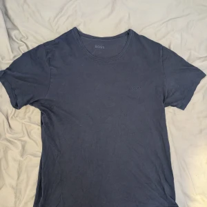 Mörkblå BOSS t-shirt - Snygg mörkblå t-shirt från BOSS med diskret broderad logga på bröstet. Klassisk rund halsringning och korta ärmar. Tillverkad i mjuk bomull som känns skön mot huden. Perfekt för en clean och stilren look. Strl L skriv för frågor, bilder och offer 🙂‍↕️