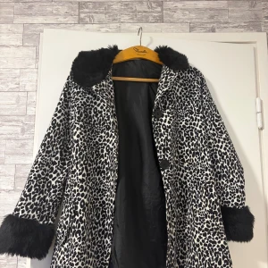 Leopardmönstrad pälsjacka från H&M - Säljer en leopardmönstrad pälsjacka från H&M med svarta fluffiga detaljer vid krage och ärmslut. Jackan har knappar framtill och är fodrad med svart tyg. 