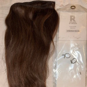 Rapunzel of Sweden Clip-on löshår 40cm - Clip-on set med äkta löshår från Rapunzel of Sweden i färgen mörkbrun (2.0). Längd 40 cm, tre delar med lätt volym. Håret är rakt och fästs enkelt med clips. Perfekt för dig som vill ha längre och fylligare hår på nolltid. Använts en gång på modell under min diplomering som hårstylist. Så nästan nytt. Dm för fler bilder eller frågor c: