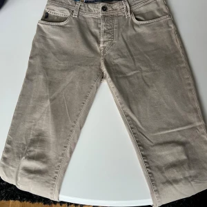 Beige jeans från tramarossa  - Snygga beige jeans från tramarossa , tillverkade i Italien. Klassisk femficksmodell med silverfärgade knappar och detaljer. Materialet är mjuk bomull och passformen är normal. Perfekta för dig som gillar stilrena och enkla plagg med snygga detaljer. 