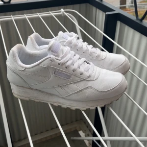 Vita Reebok sneakers i skinn, strl 36 - Klassiska vita Reebok sneakers i skinn med snygga detaljer och låg profil. Skorna har snörning, platt sula och rund tå. Perfekta för dig som gillar en clean och tidlös look. Storlek 36 (EU).