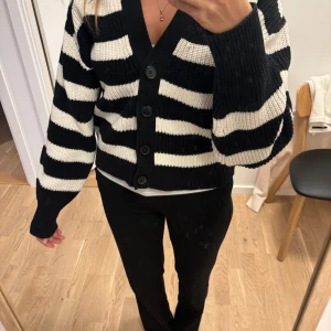 Svartvit randig kofta med knappar - Säljer en svartvit randig kofta med grovstickat material och stora svarta knappar framtill. Koftan är croppad med lång ärm och har en djup v-ringning. Den är från H&M och är i storlek S💞