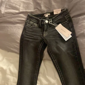 Svarta lågmidjade jeans XS - Svarta jeans från Gina Tricot i storlek XS med låg midja bootcut och markerade vita sömmar. Modellen har klassiska fem fickor och snygga detaljer på bakfickan. Perfekt för dig som gillar en cool och trendig look.