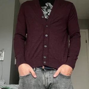 Vinröd kofta i merinoull från GAP - Vinröd kofta i merinoull som är riktigt skön. Står M på etikett men passar mer som en S enligt mig. Jag är 185 cm och 75 kg 