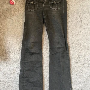 Svarta bootcut jeans från Gina Tricot - Snygga svarta jeans från Gina Tricot med bootcut passform och coola fickdetaljer fram. Jeansen har vita kontrastsömmar, knapp och dragkedja i midjan samt klassiska bakfickor. Perfekta för dig som gillar en lite retro vibe.