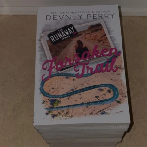Forsaken Trail - En bok från The Runaway Series av Devney Perry. Omslaget visar en ung person på en öde väg och en slingrande väg genom ett ökenlandskap. Perfekt för dig som gillar spännande berättelser om resor och nya äventyr.
