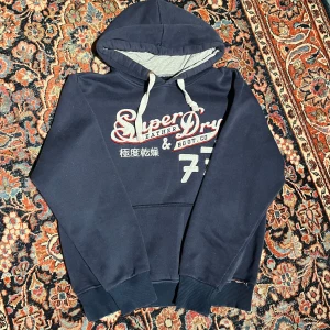Vintage Superdry hoodie - Riktigt cool vintage Superdry hoodie! Denna har riktigt feta detaljer och färger! Mått: Bredd:47cm Längd:58cm