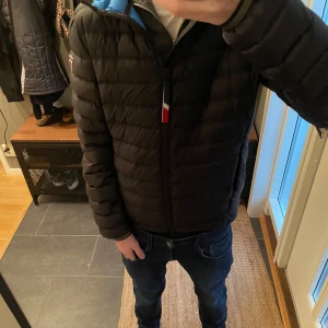 Svart dunjacka från Rossignol med huva - Snygg svart dunjacka från Rossignol med blått foder och huva. Jackan har quiltad design, dragkedja framtill och logotyp på ärmen. Perfekt för kalla dagar och har en clean look med diskreta detaljer. Passar dig som gillar sportiga och stilrena jackor. Jackan är knappt använd och är 10/10 skick. Den passar xs.