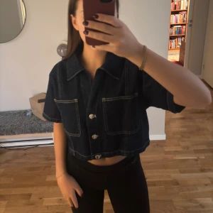 Mörkblå croppad jeansskjorta - Croppad skjorta i mörkblå denim från Zara med korta ärmar, aldrig kommit till användning och har prislapp kvar🥰