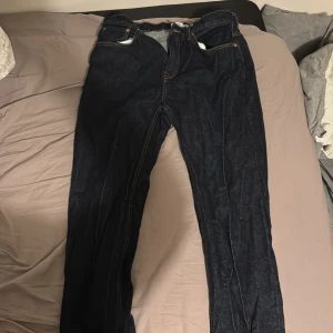 Mörkblå jeansbyxor med raka ben - Snygga mörkblå jeansbyxor med klassisk femficksdesign och kontrastsömmar. Modellen har raka ben och normal passform, perfekt för dig som gillar en enkel och tidlös stil. Materialet är slitstarkt jeans och midjan är klassisk.