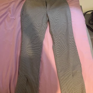 Rutig kostymbyxa Twist & Tango 36 - Snygga kostymbyxor från Twist & Tango i storlek 36. Byxorna har ett klassiskt rutmönster i svart och vitt, rak passform och medelhög midja. Perfekt för dig som gillar stilrena och trendiga plagg med lite edge.