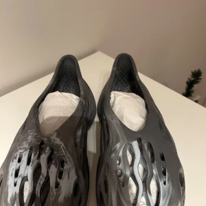 Gråsvarta foam sandaler Yeezy-inspirerade - Unika sandaler i Yeezy foam runner-stil med coolt marmorerat mönster i grått och svart. Skorna har en futuristisk design med många öppningar för extra ventilation och är tillverkade i lätt syntetmaterial. Perfekta för dig som vill sticka ut med en modern vibe.⚠️1:1⚠️