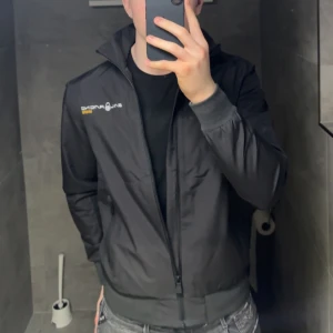 Totalt oanvänd Sail Racing - Svart vindjacka från Sail Racing med GORE-TEX-material. Jackan har dragkedja framtill, ståkrage och ribbade muddar. Diskreta loggor i vitt och gult på bröstet och ryggen. Köpte den på impuls och märkte att den var aningen för kort i armar och längd på 180 cm, 80 kg. Kostar 3-4 tusen ny.