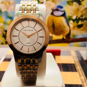 Leijona Damklocka i silver och guld - Stilren Leijona klocka med rund vit urtavla, guldfärgade visare och index. Boetten är i guldtonad metall och armbandet är i rostfritt stål med både silver- och guldfärgade länkar. Vattentät till 5 ATM och har en klassisk, tidlös design.Säljes i befintligt skick enligt bilderna .Nytt batteri, fungerar utmärkt!