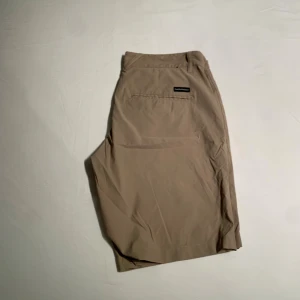 Beige shorts från Peak Performance - Snygga beige shorts från Peak Performance med klassisk passform och raka ben. De har två bakfickor och bälteshällor i midjan. Perfekta för varma dagar och stilrena till både t-shirt och skjorta.