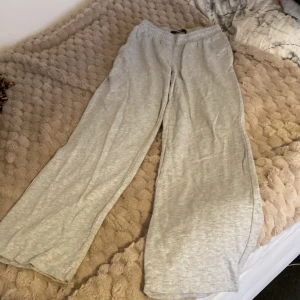 Låg midjade Grå mjukisbyxor med breda ben - Superbekväma grå mjukisbyxor med bred resår i midjan, låg midjade och raka, vida ben. Perfekta för chill dagar eller när du vill ha något riktigt skönt på dig. Tillverkade i mjukt bomullsmaterial som känns skönt mot huden.