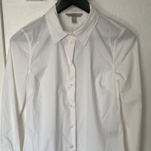 Vit skjorta från H&M i XS - Klassisk vit skjorta från H&M i storlek XS. Skjortan har lång ärm, spetsig krage och knappar framtill. Tillverkad i mjuk bomull som känns skön mot huden. Perfekt för dig som gillar en clean och stilren look.