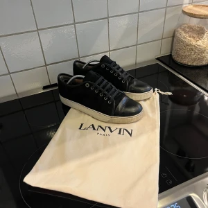 Lanvin cap toe - Snygga svarta sneakers från Lanvin Paris med vit sula och klassisk låg profil. Skorna är i bra skick ungefär 8/10. Box ingår och såklart är skorna helt äkta. Skorna är i storlek 41 men passar även större. Skriv vid minsta fundering om pris mm.