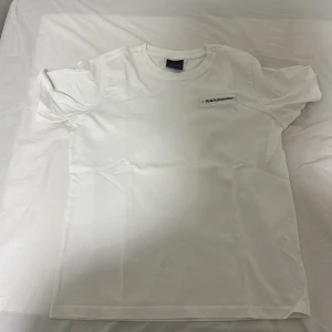 Vit Peak Performance t-shirt - Vit t-shirt från Peak Performance med klassisk rund hals och diskret logotyp på bröstet. Enkel och stilren design i mjuk bomull, perfekt för en clean look. Kortärmad modell som passar till det mesta.